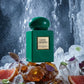 Un plan moyen d'un flacon de parfum vert émeraude, image_0.png, reposant sur une formation de pierre d'ambre brut et des cristaux de quartz clairs. Derrière lui, une cascade d'eau glacée est capturée en mouvement lent, créant un brouillard fin. L'éclairage est froid, théâtral, soulignant la plaque dorée de image_0.png. Des feuilles de violette et de petits pétales de rose verte sont délicatement posés sur les rochers, avec des éclats de pamplemousse rose. Style : Photographie d'art conceptuelle, hyper-détai