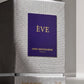 Un plan macro très serré et frontal sur la boîte texturée de image_3.png, en studio. L'éclairage est rasant pour accentuer la trame gaufrée du coffret. Le centre de l'image est la plaque violette avec le texte 'ÈVE GRIS MONTAIGNE PARIS' doré, qui est parfaitement net. La base argentée et l'inscription 'Extrait de parfum' sont visibles. Style : Photographie d'architecture d'intérieur minimaliste. (gemini-3-pro-image-preview)