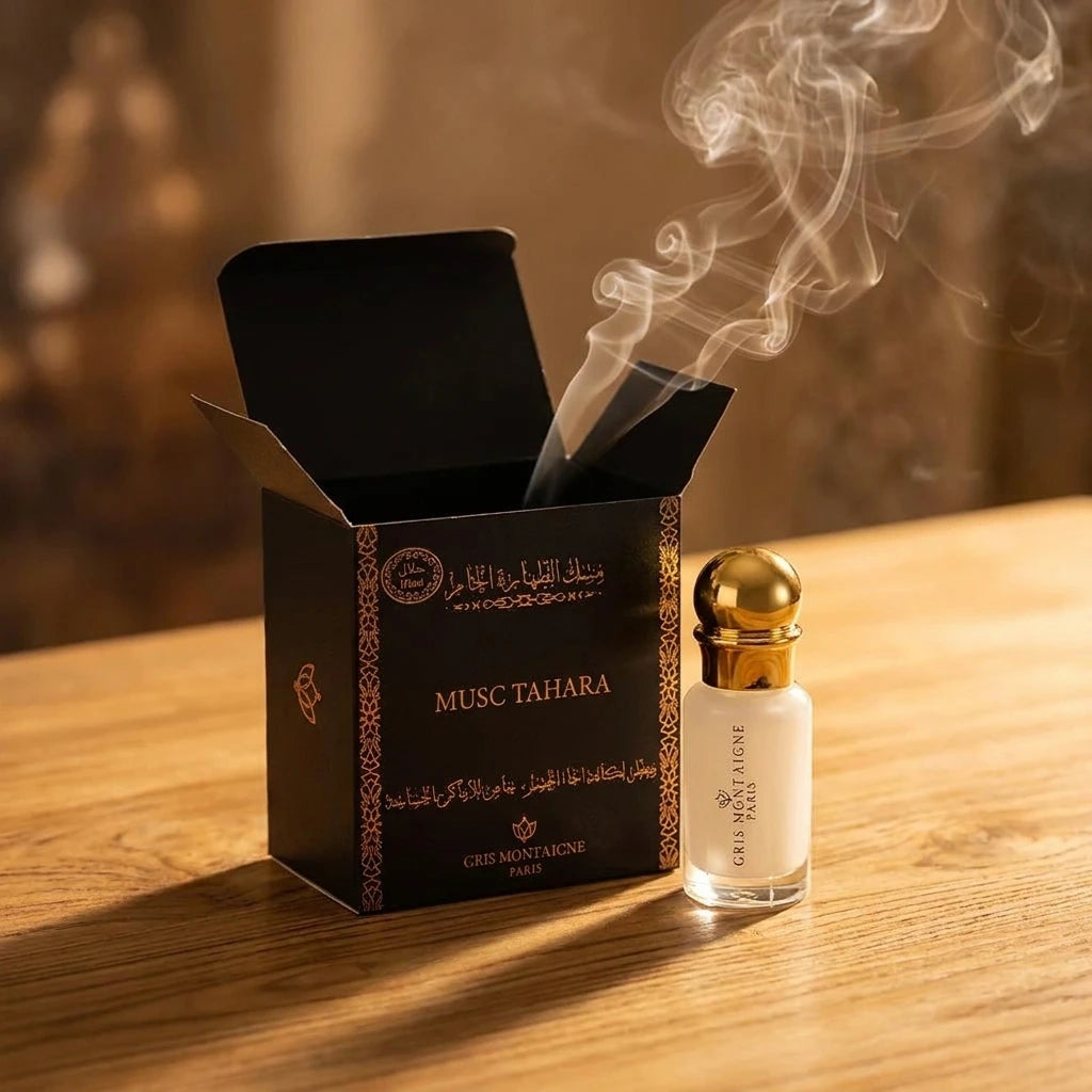 Un plan large à 45 degrés du coffret ouvert de image_17.png avec son flacon blanc et or disposé juste à côté sur une table en bois de santal clair. Une fine volute de fumée d'encens oud ou d'un bakhoor traditionnel traverse la composition de manière réaliste. L'éclairage est chaleureux et tamisé, créant une atmosphère de rituel de parfumage sacré. Style : Campagne de marque artistique. (gemini-3-pro-image-preview)