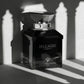 Un plan moyen du flacon de image_29.png posé contre un mur minimaliste gris clair texturé. Un projecteur puissant projette l’ombre graphique, nette et poétique de colonnes d'une villa italienne directement sur le fond et en partie sur le flacon de image_29.png. L'éclat métallique du capuchon et l'argent des lettrages apportent les seuls points lumineux de la scène. Style : Composition éditoriale moderne et graphique. (gemini-3-pro-image-preview)