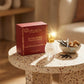 Un plan large oblique du coffret et du flacon de image_2fd2a0.jpg disposés sur une table d'appoint moderne en terrazzo beige et rouge. À côté des produits, une petite coupelle artisanale en céramique contient des éclats de vanille noire et des morceaux de sucre roux. Un rayon de soleil réaliste traverse la scène, créant un éclat brillant intense sur le capuchon doré de image_2fd2a0.jpg. Style : Campagne publicitaire lifestyle et gourmande. (gemini-3-pro-image-preview)